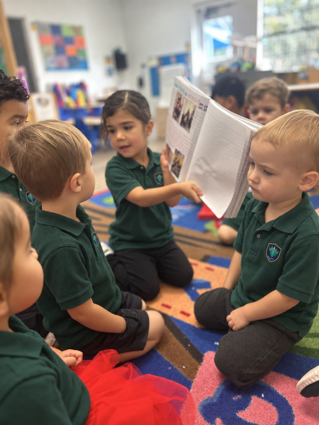 Children in green school polos reading together on the classroom rug